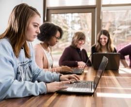 students working at a table with computers.